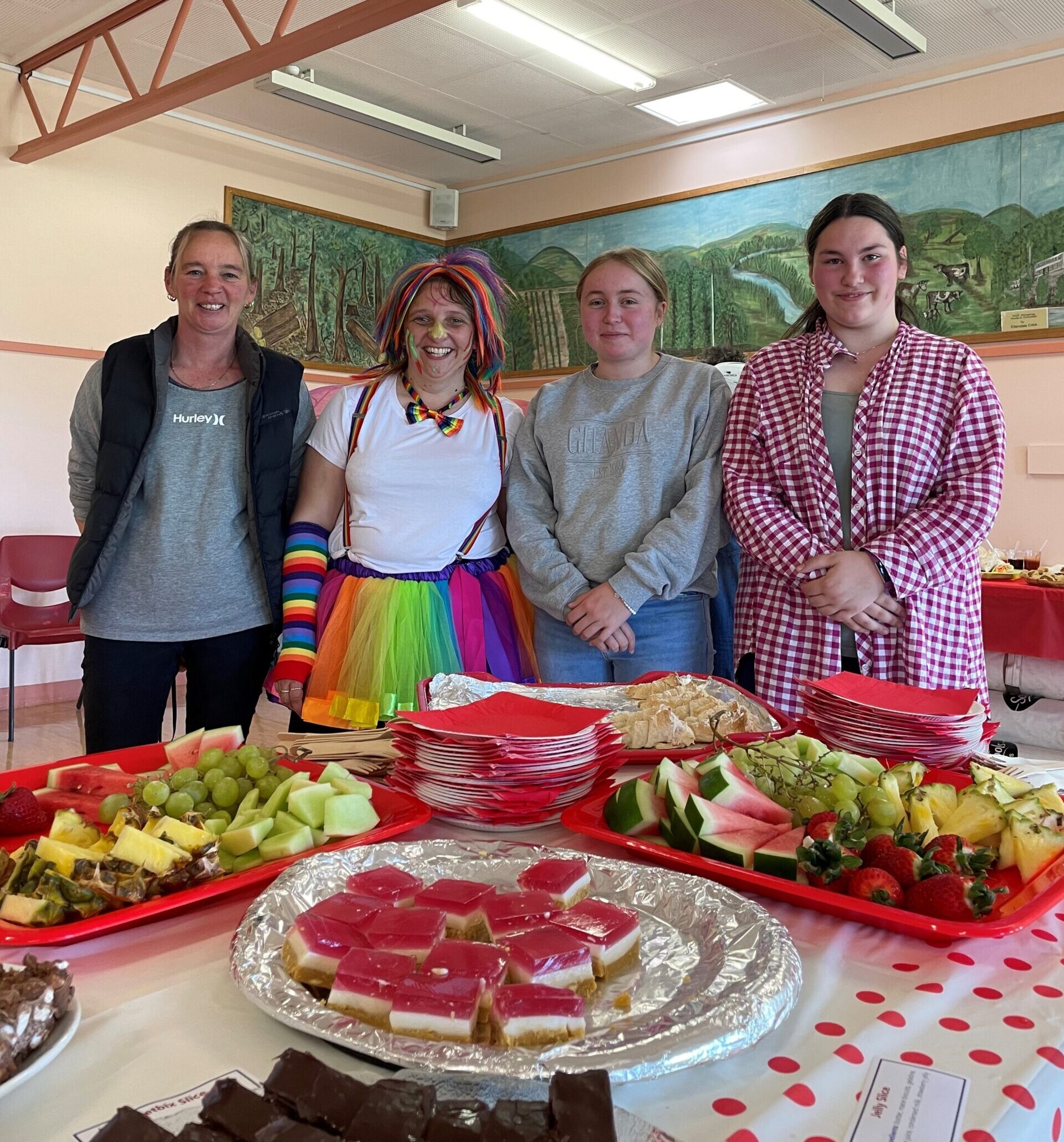 three women and one man volunteering to help serve breakfast in front of plates of fruit and jam tarts